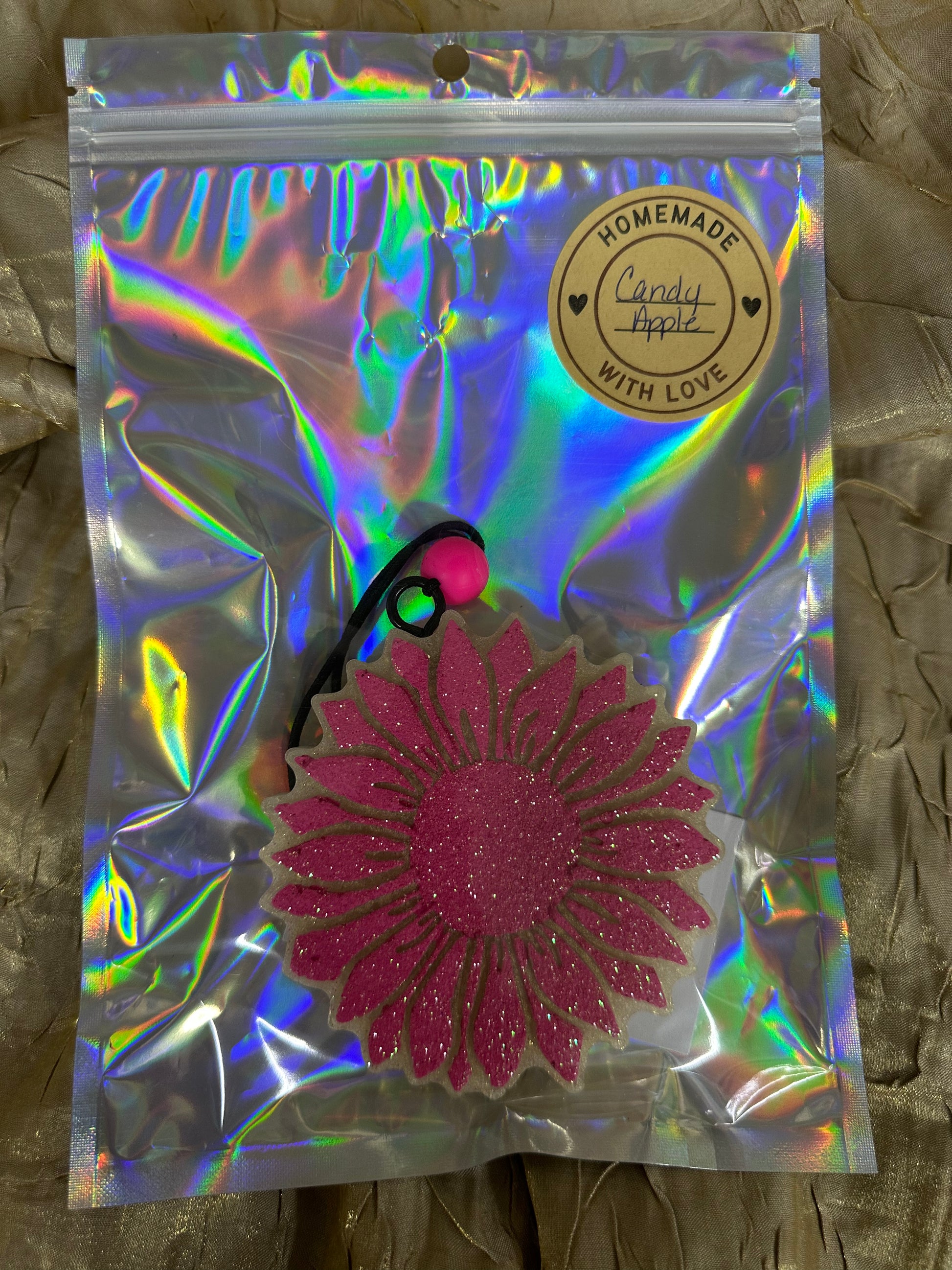 Holographic packaging with a pink flower-shaped object on a textured surface