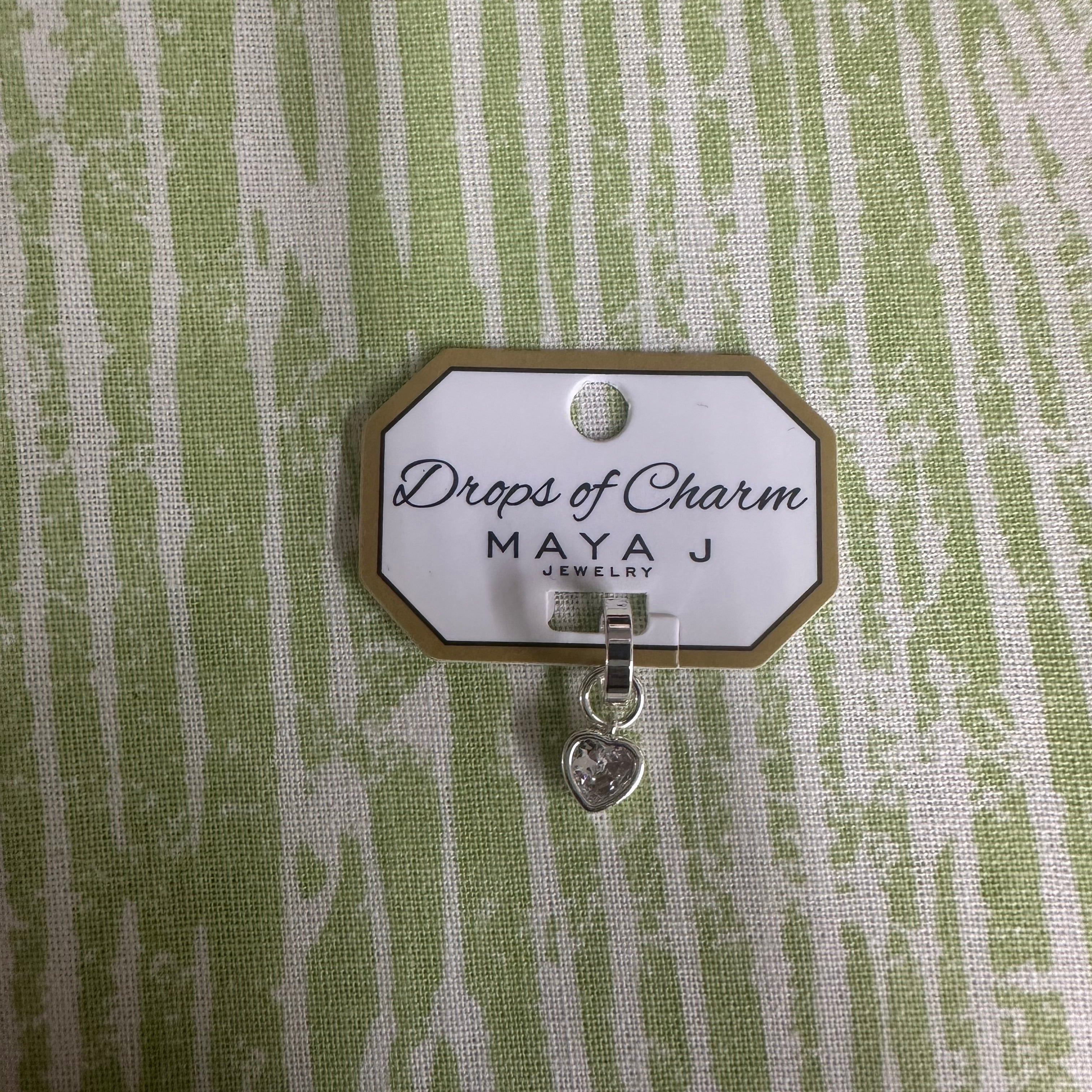 Heart charm in white gold on a textured green background 