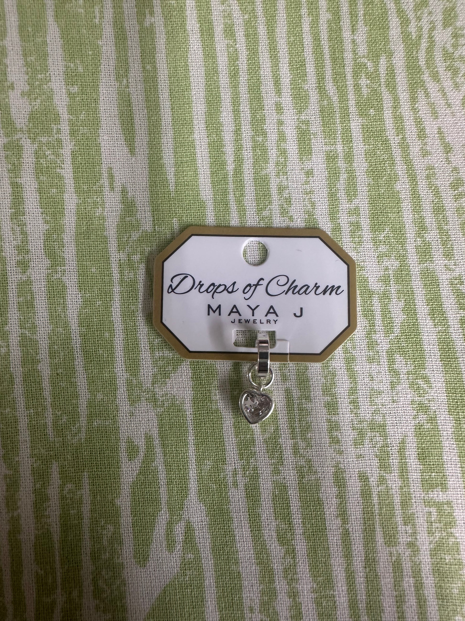Heart charm in white gold on a textured green background 