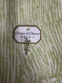 White gold charm with 'Drops of Charm' text on a textured green background