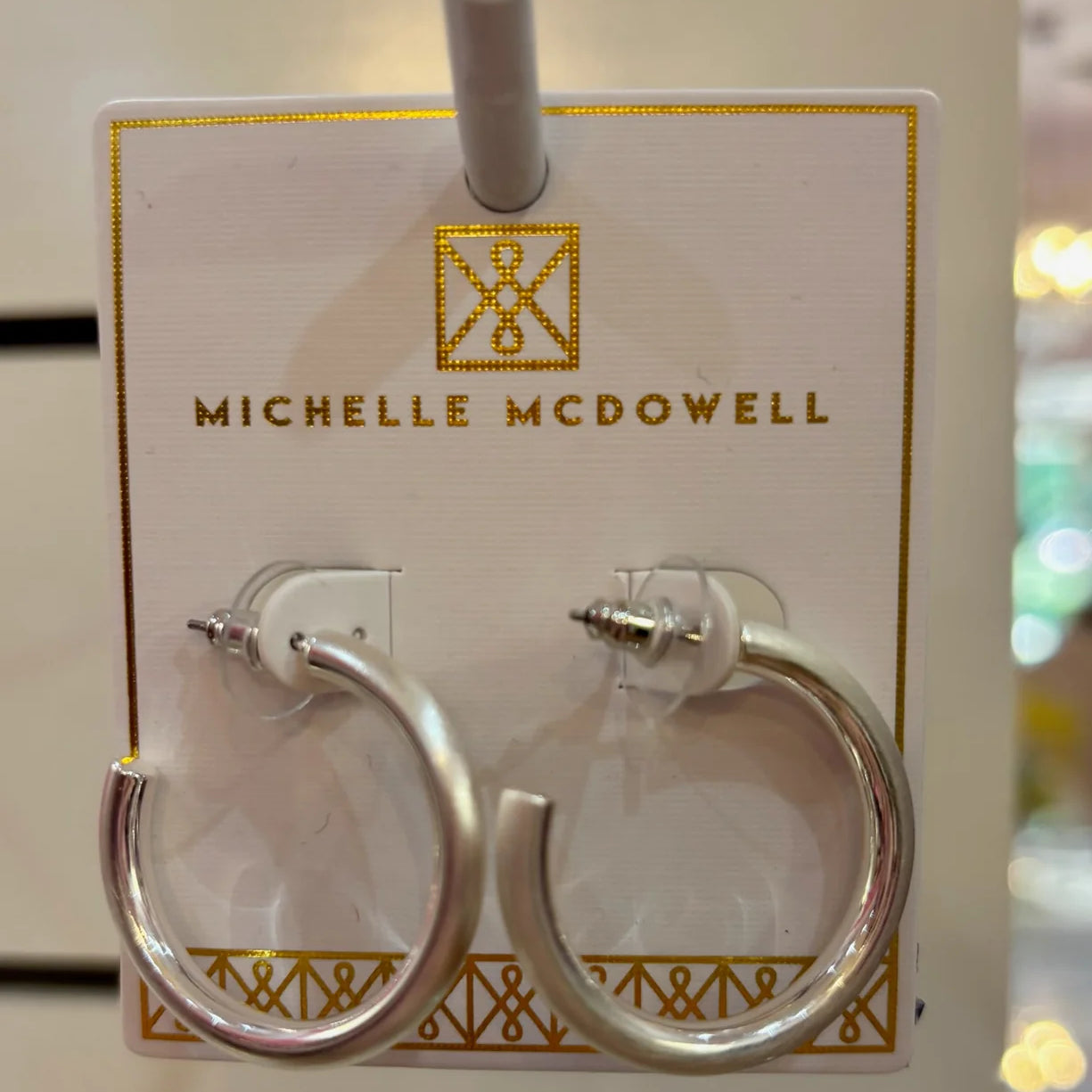 Silver hoop earrings on a branded card with 'Michelle McDowell' logo.