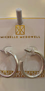 Silver hoop earrings on a branded card with 'Michelle McDowell' logo.