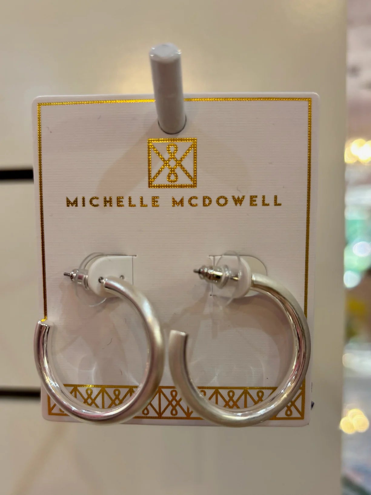 Silver hoop earrings on a branded card with 'Michelle McDowell' logo.