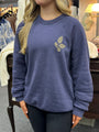 Person wearing a blue sweatshirt with a leaf design in a casual setting