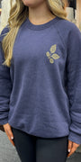 Person wearing a blue sweatshirt with a leaf design in a casual setting