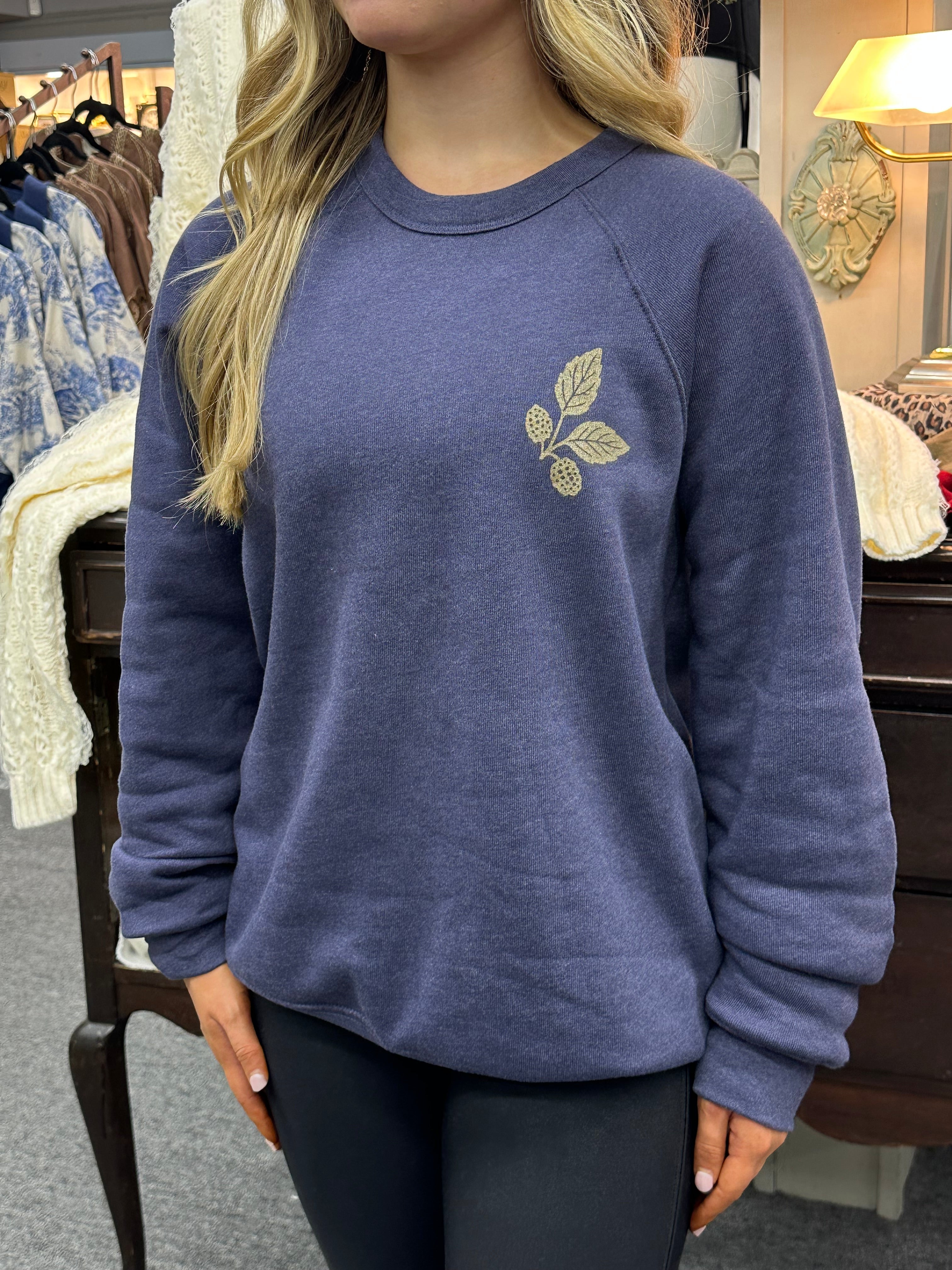 Person wearing a blue sweatshirt with a leaf design in a casual setting