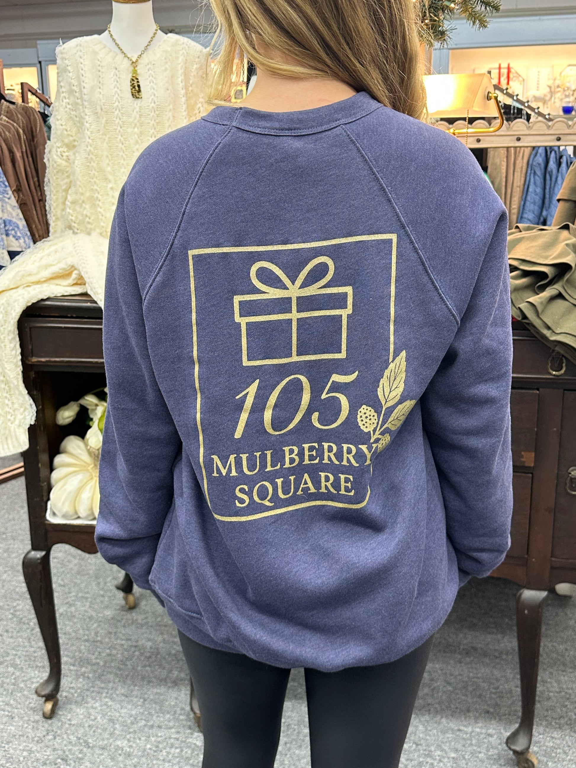 Person wearing a blue hoodie with '105 Mulberry Square' logo.