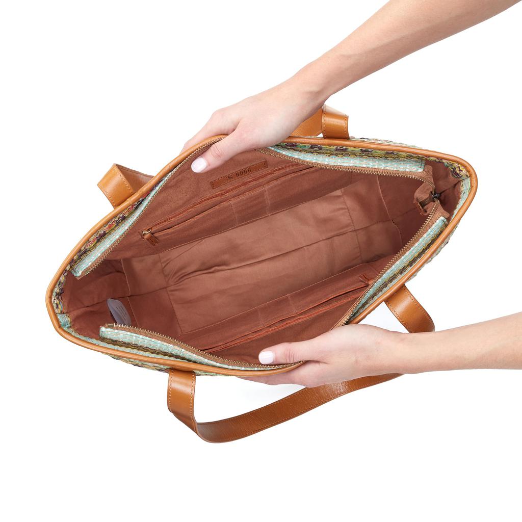 Brown leather bag held open by hands on a white background