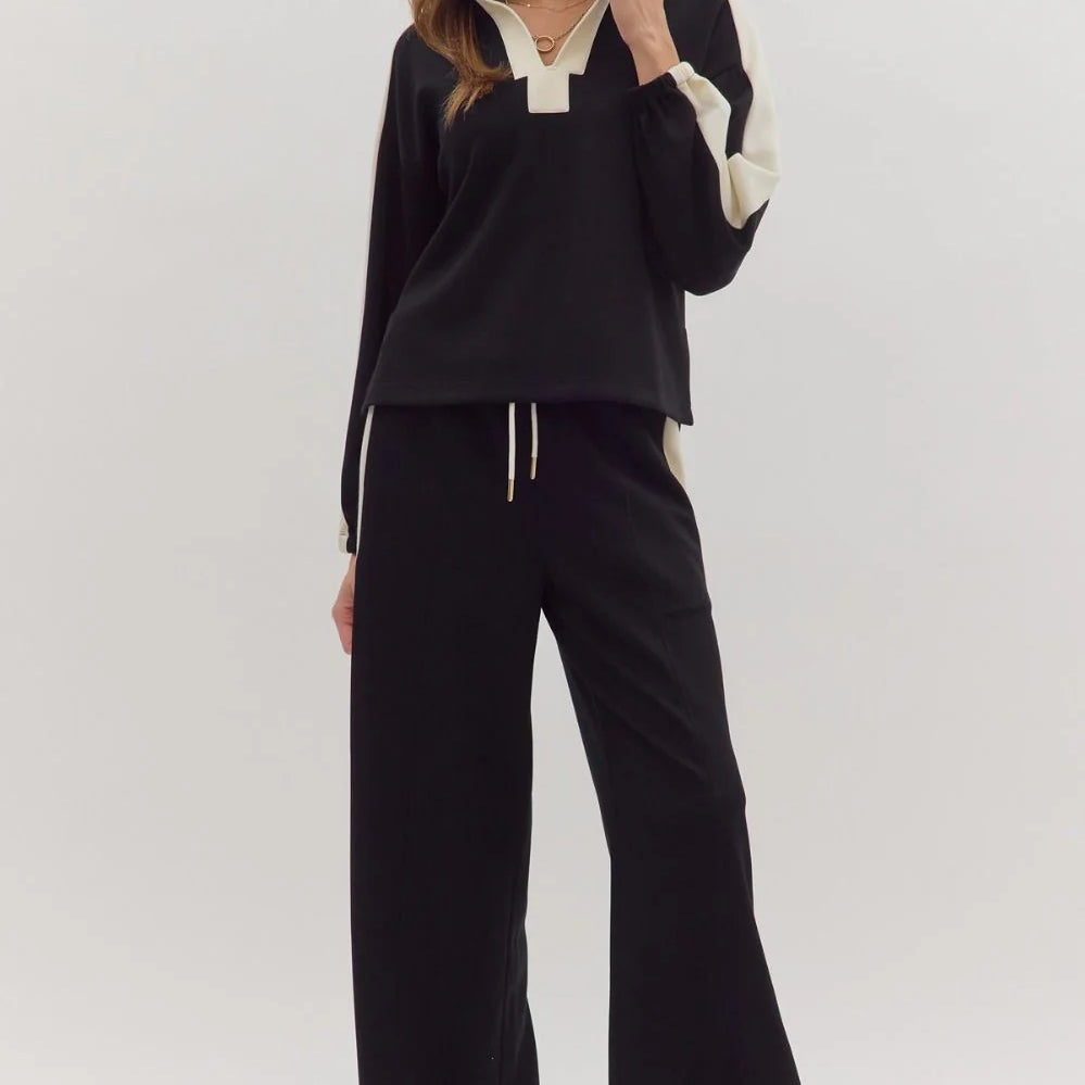 Woman wearing a black outfit with white accents on a white background