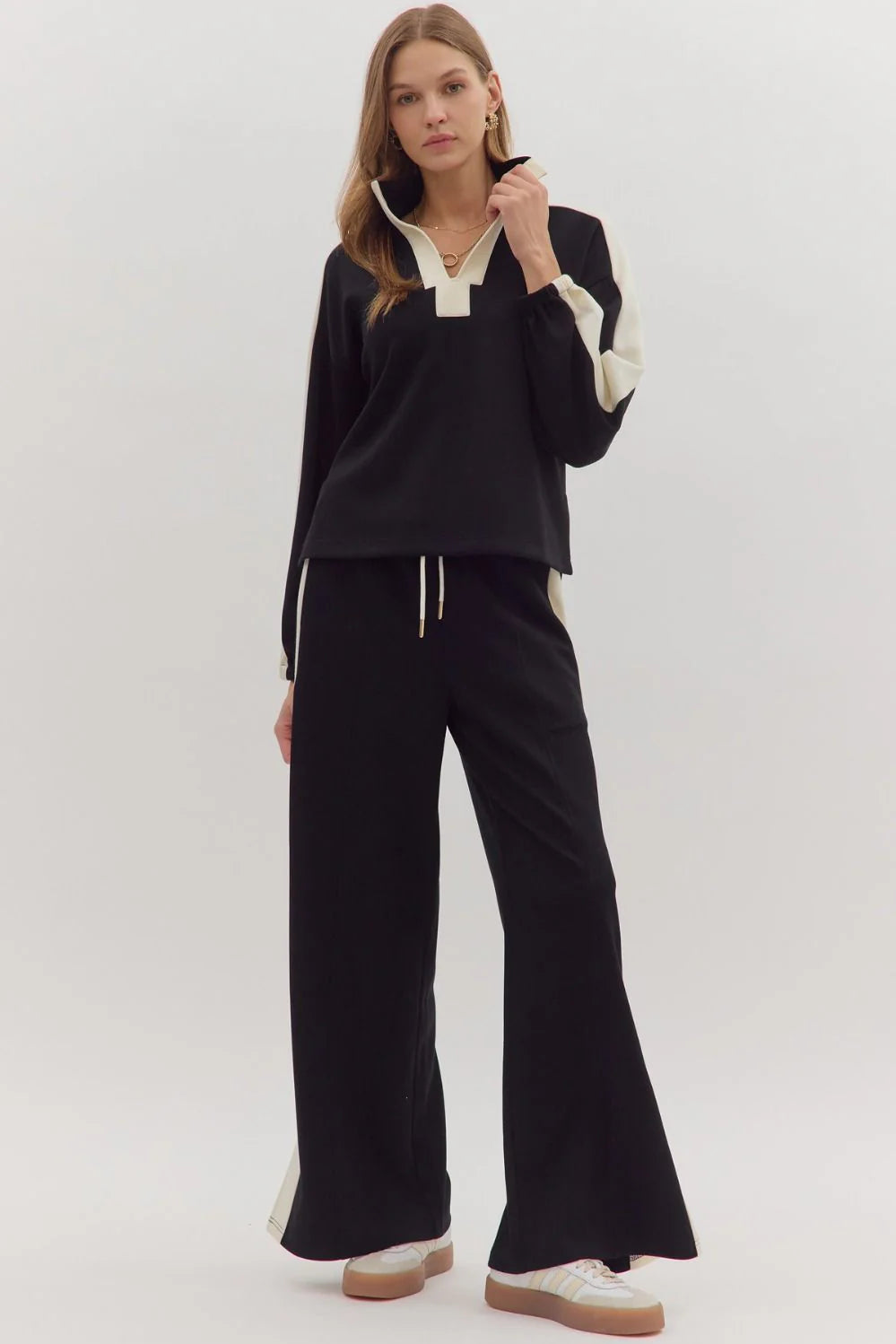 Woman wearing a black outfit with white accents on a white background