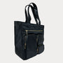 Black tote bag with gold zippers on a light gray background