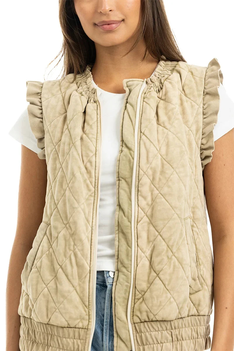 Woman wearing a beige quilted vest over a white shirt on a white background