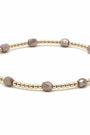 Bracelet with gold and mauve beads on a white background