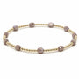 Bracelet with gold and mauve beads on a white background