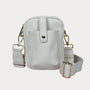 Light gray crossbody bag with gold accents on a white background