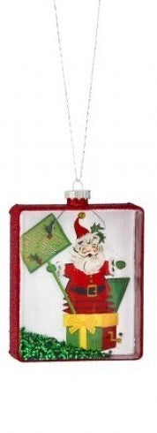 Square glass Santa ornament with red frame, Santa holding gifts and a decorated tree