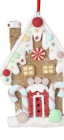 A gingerbread house Christmas ornament with white icing details, candy decorations, a red door, and a red hanging ribbon on a white background.