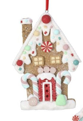 A gingerbread house Christmas ornament with white icing details, candy decorations, a red door, and a red hanging ribbon on a white background.