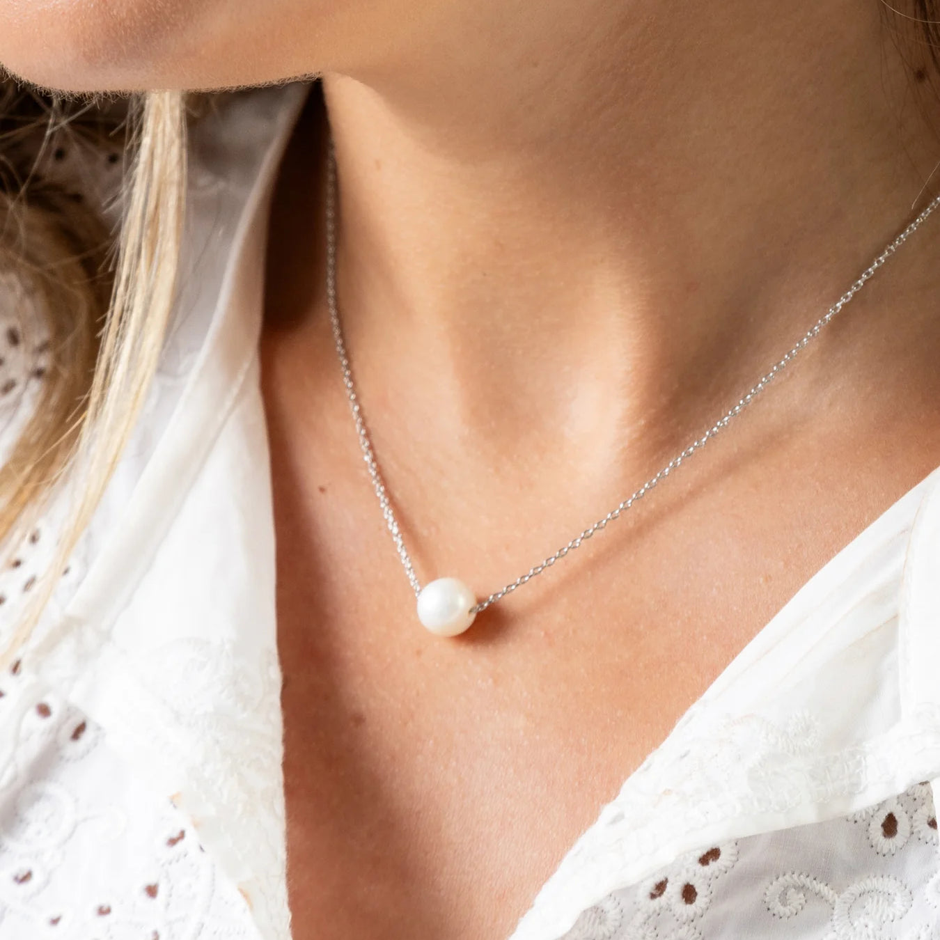 Pearl necklace worn by a person with a white blouse