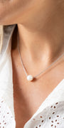 Pearl necklace worn by a person with a white blouse