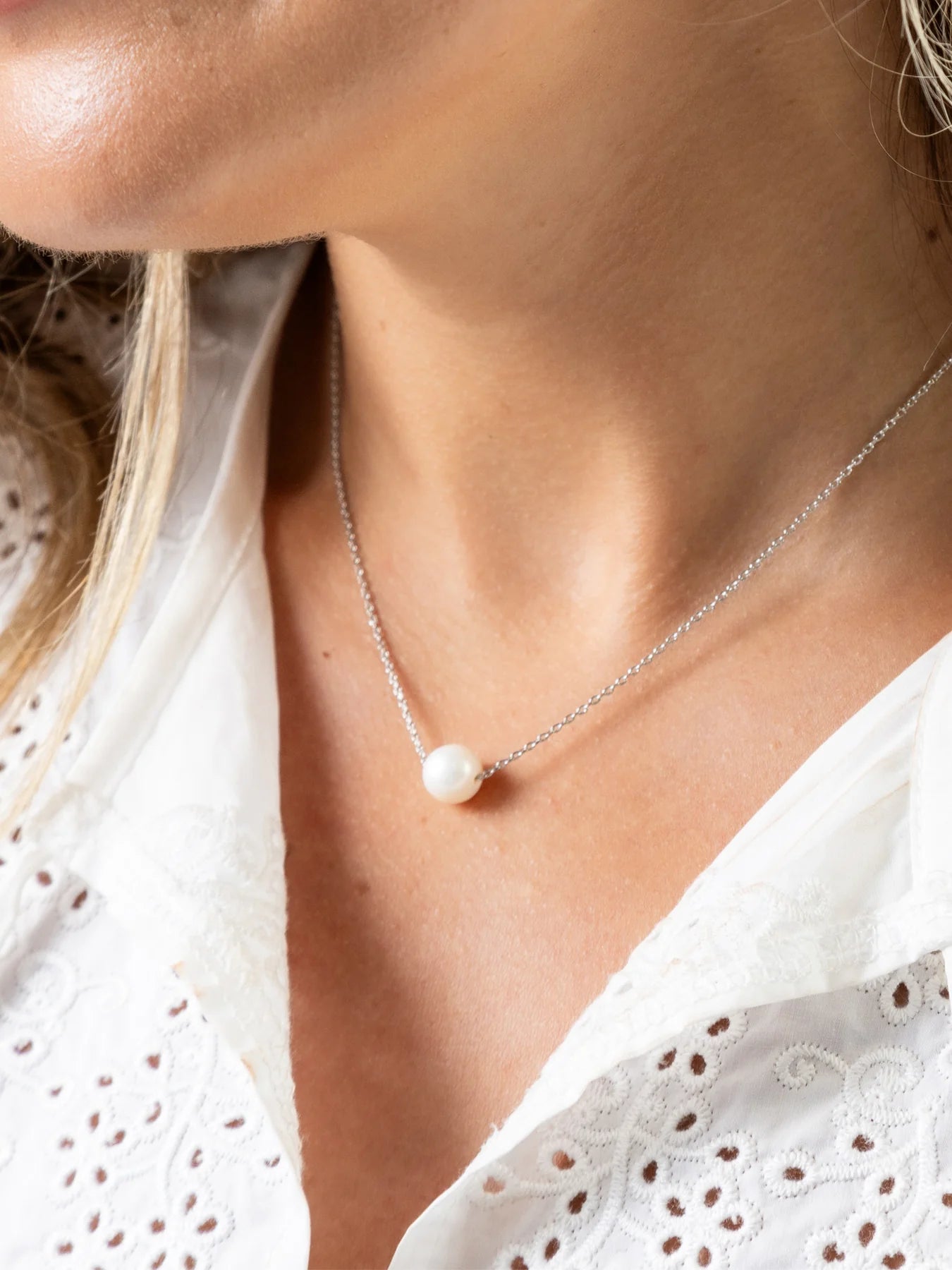 Pearl necklace worn by a person with a white blouse