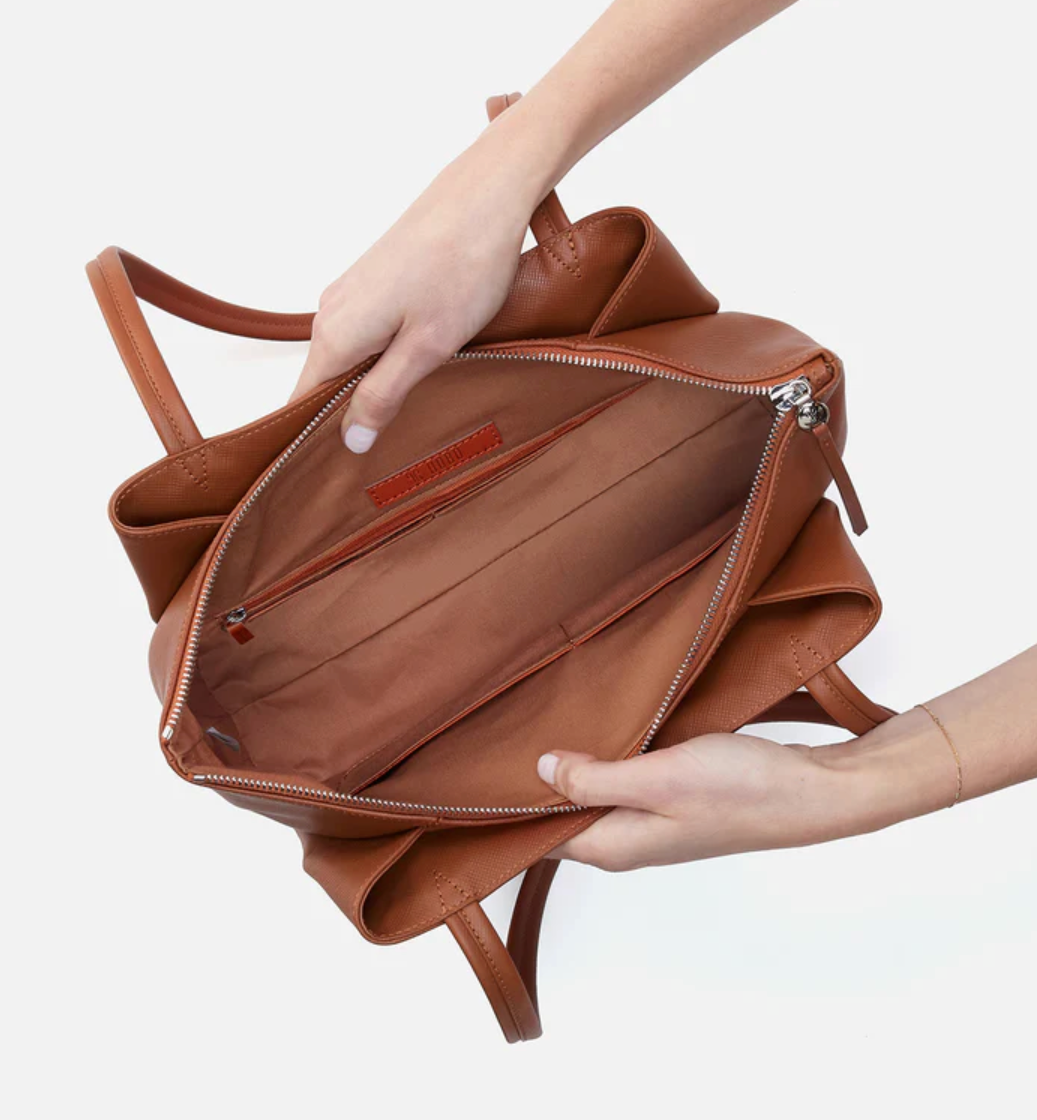 Brown leather bag held by a person on a white background