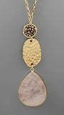 A gold-tone dangle necklace featuring a textured hammered oval pendant, a small round bezel-set cluster of dark brown stones, and a large teardrop-shaped pale pink stone pendant, shown against a solid gray background.