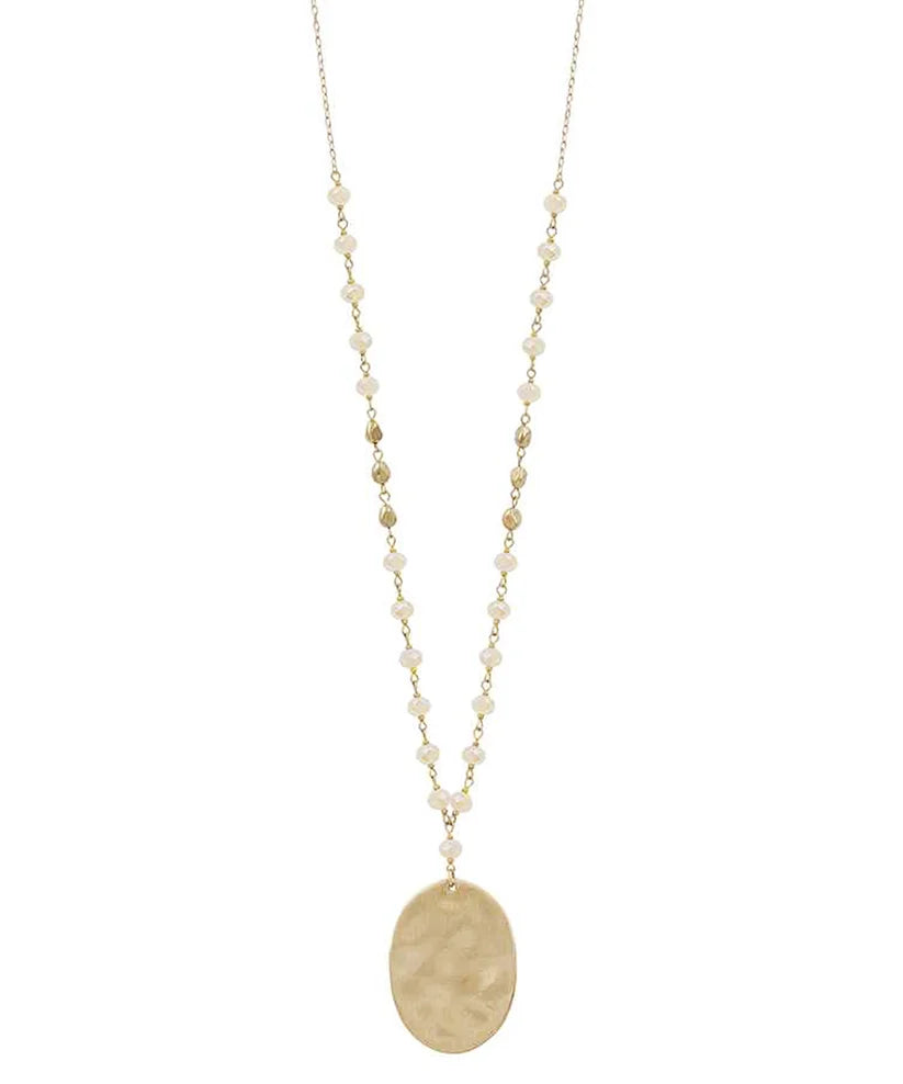 A long gold-tone chain necklace featuring small cream-colored faux pearls and gold beads spaced along the chain, with a large oval gold pendant hanging at the center, shown against a plain white background.