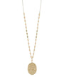 A long gold-tone chain necklace featuring small peach-colored beads spaced along the chain and a large, flat oval pendant with a textured finish, shown against a plain white background.