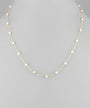 A delicate gold chain necklace featuring evenly spaced, small white pearl beads, displayed on a neutral gray background.