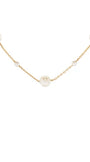A delicate gold chain necklace featuring several round, off-white faux pearl beads spaced along the chain, shown against a plain white background.