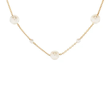 A delicate gold chain necklace featuring several round, off-white faux pearl beads spaced along the chain, shown against a plain white background.