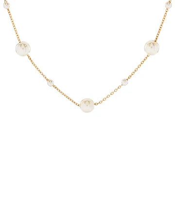 A delicate gold chain necklace featuring several round, off-white faux pearl beads spaced along the chain, shown against a plain white background.