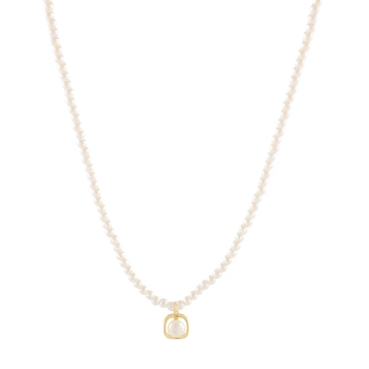 A delicate pearl necklace with a small gold pendant on a solid white background.