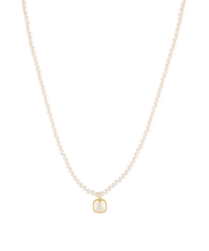 A delicate pearl necklace with a small gold pendant on a solid white background.