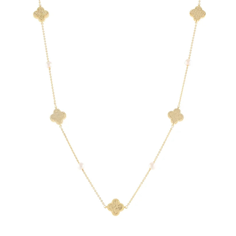 A delicate gold chain necklace featuring five textured gold quatrefoil (clover) charms spaced evenly along the chain, with small pale pink beads interspersed, set against a solid white background.