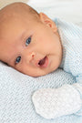 Newborn baby lying on a textured blanket wearing a light blue outfit.