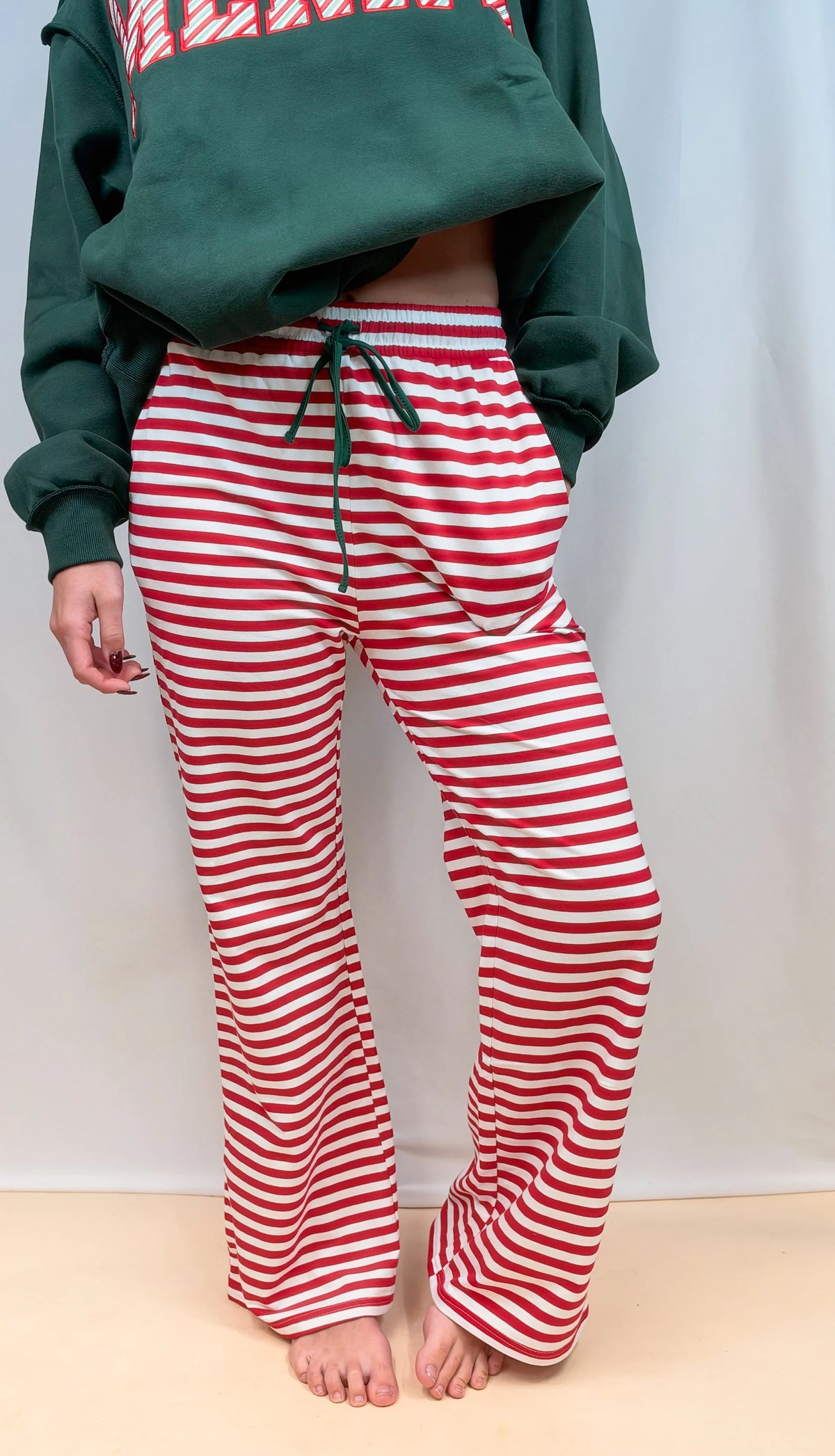 Red and white striped track pants with green drawstring waist and straight legs