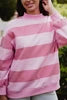 Person wearing a pink and white striped sweater with a blurred outdoor background
