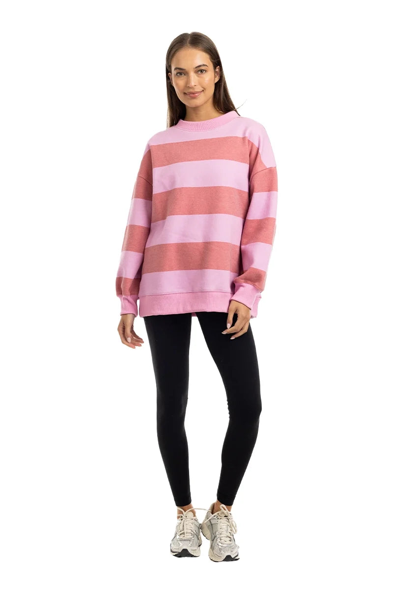 Woman wearing a pink and red striped sweater with black leggings on a white background