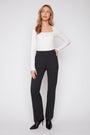 Woman wearing a white long-sleeve top and black pants on a white background
