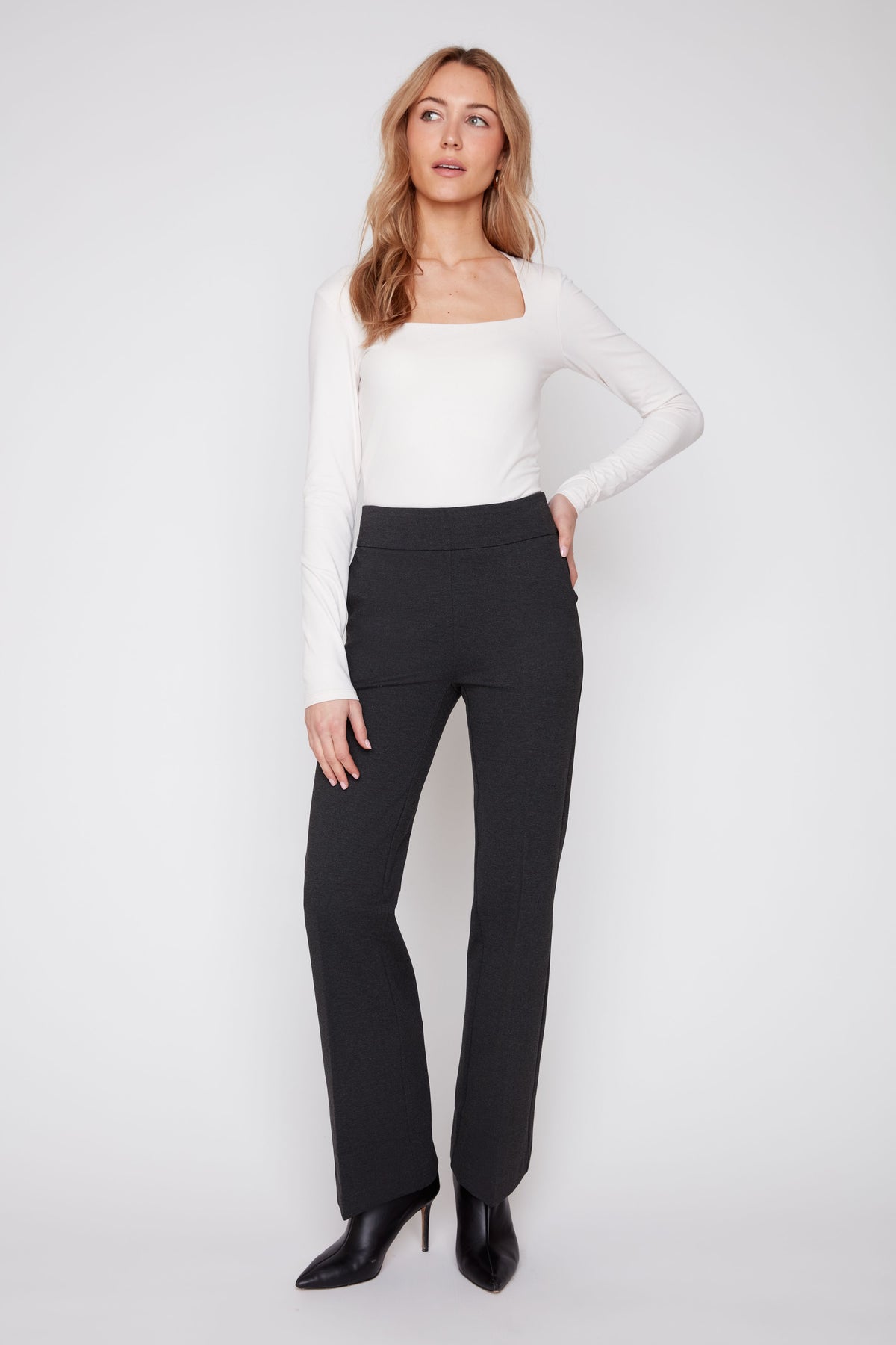 Woman wearing a white long-sleeve top and black pants on a white background