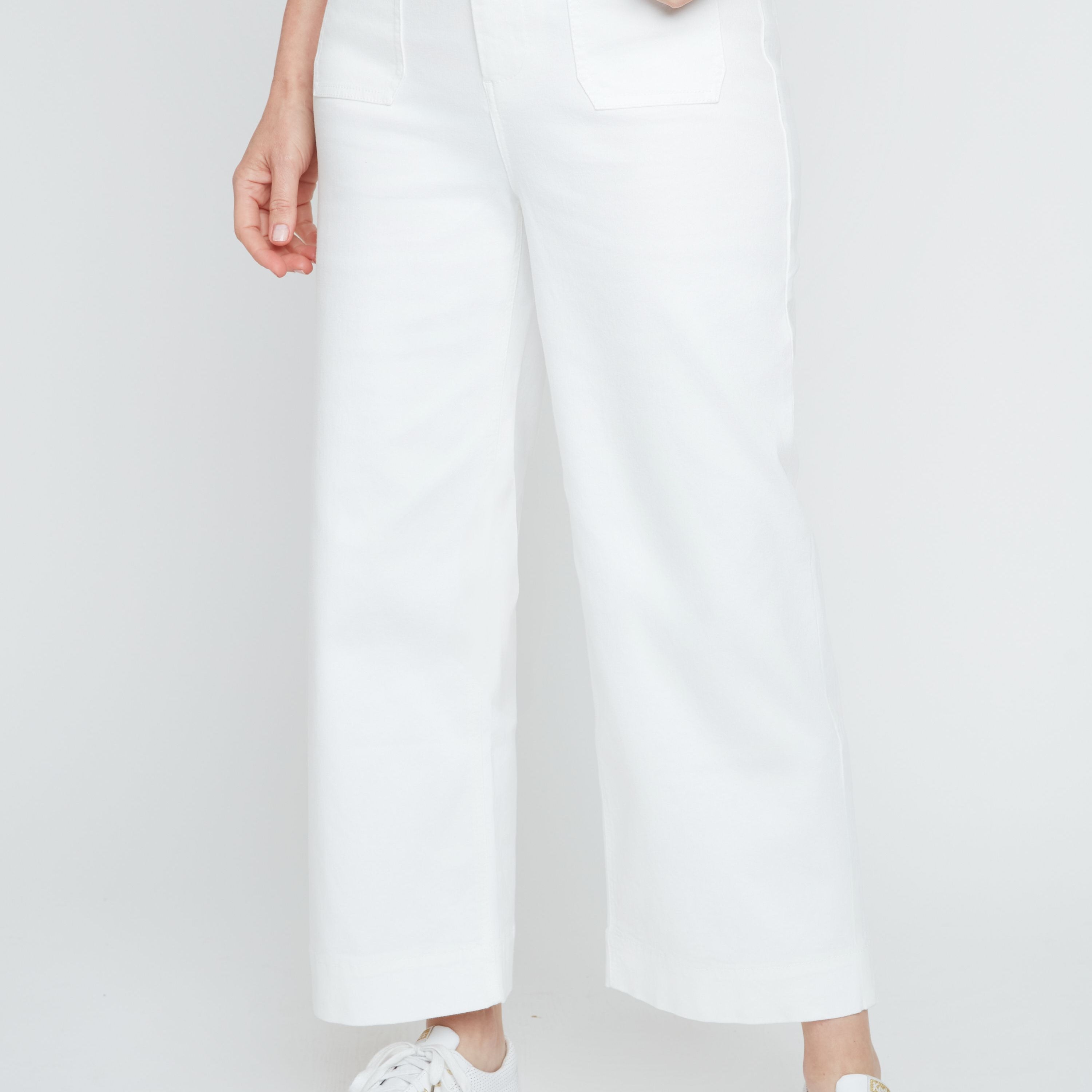 Person wearing white pants and white sneakers on a plain background
