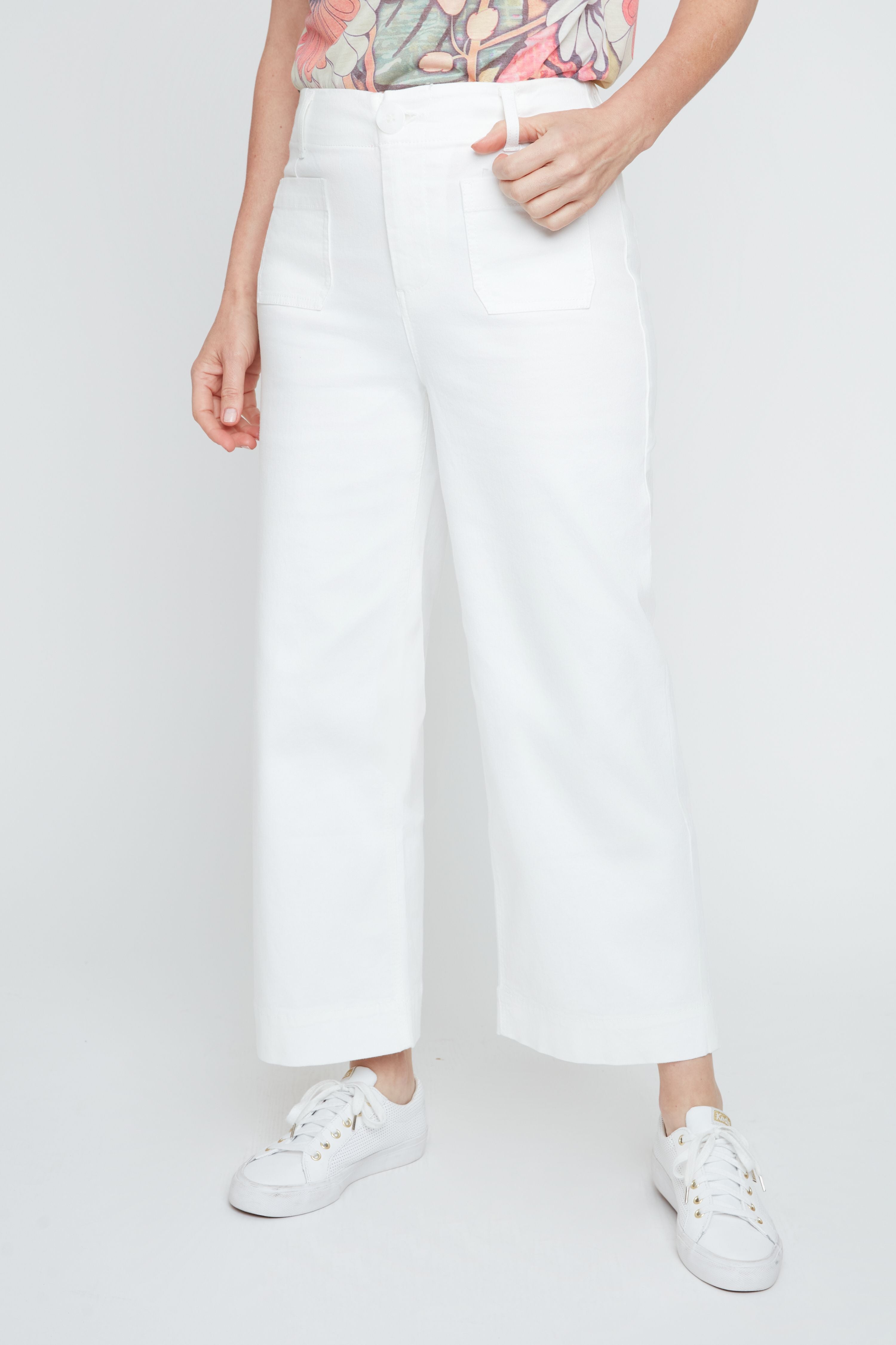 Person wearing white pants and white sneakers on a plain background