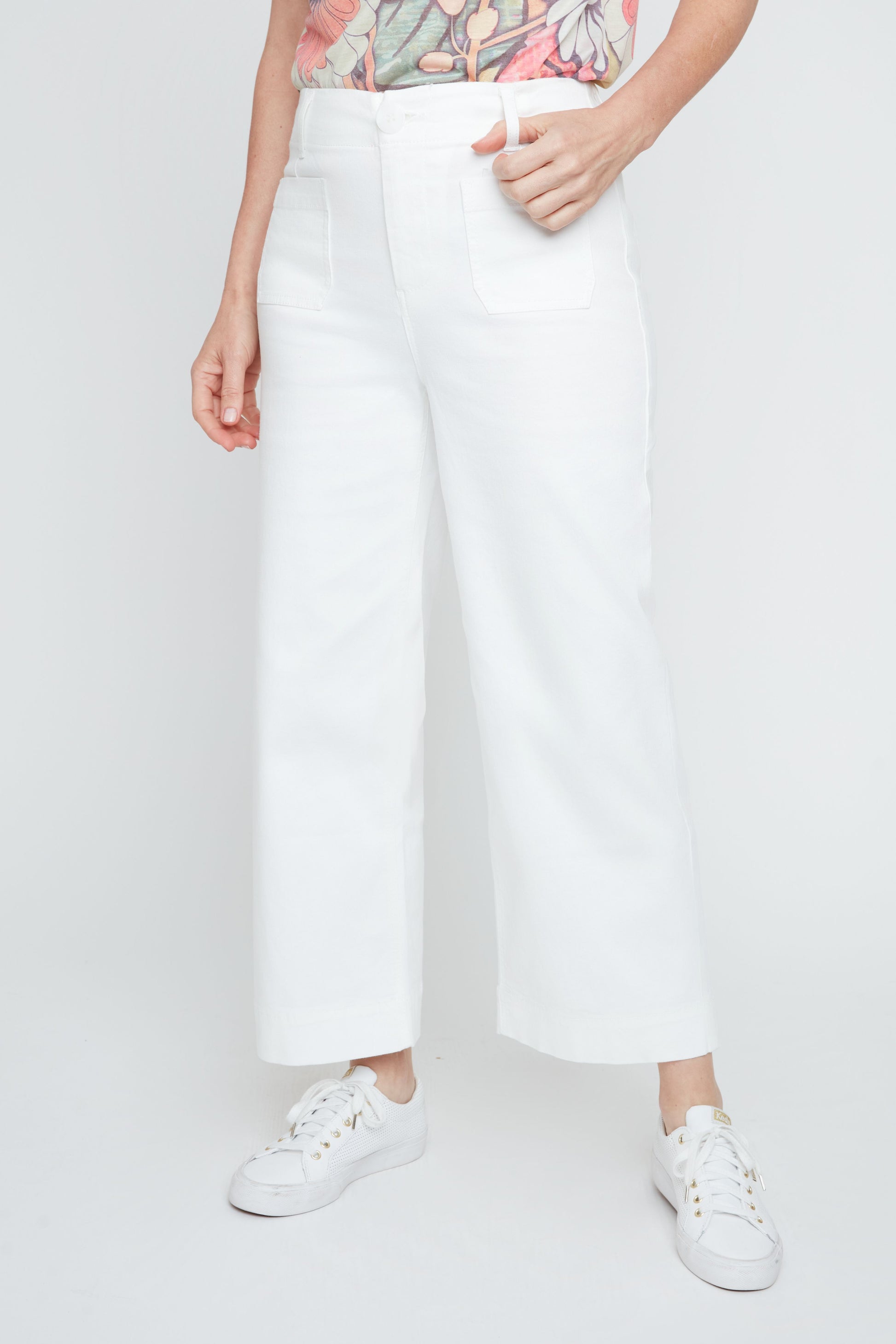 Person wearing white pants and white sneakers on a plain background