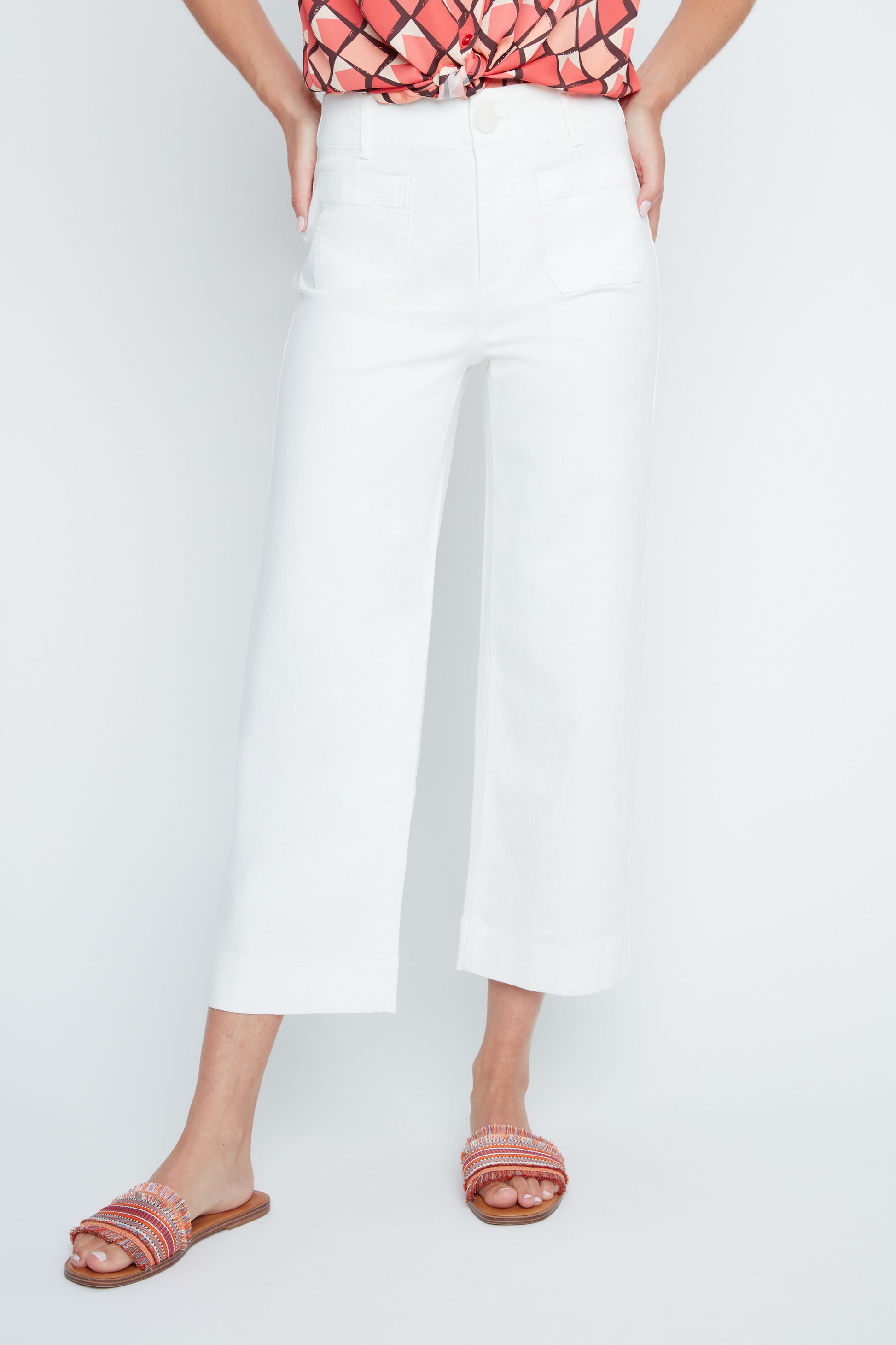 Person wearing a white skirt and pink sandals on a light gray background