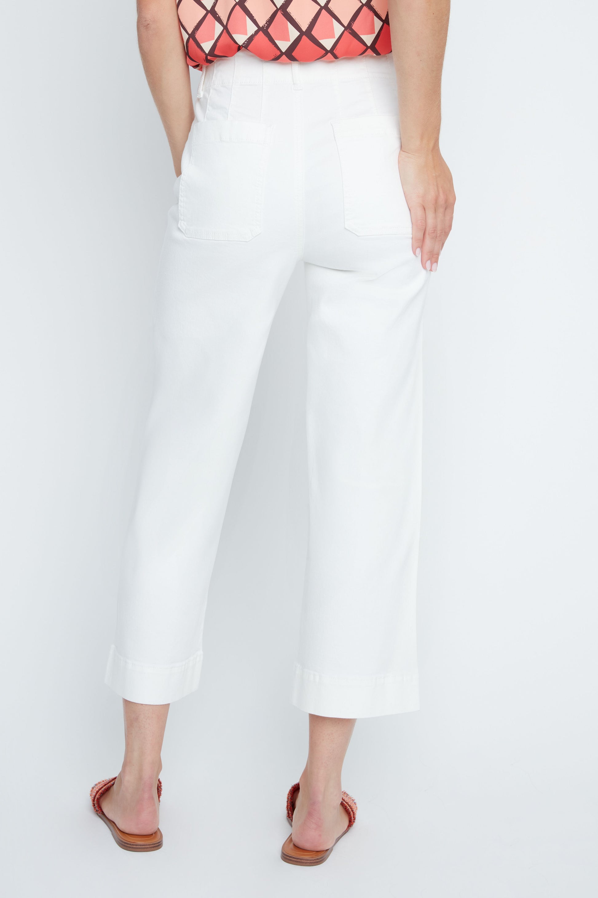 Person wearing white pants and a red patterned top on a white background
