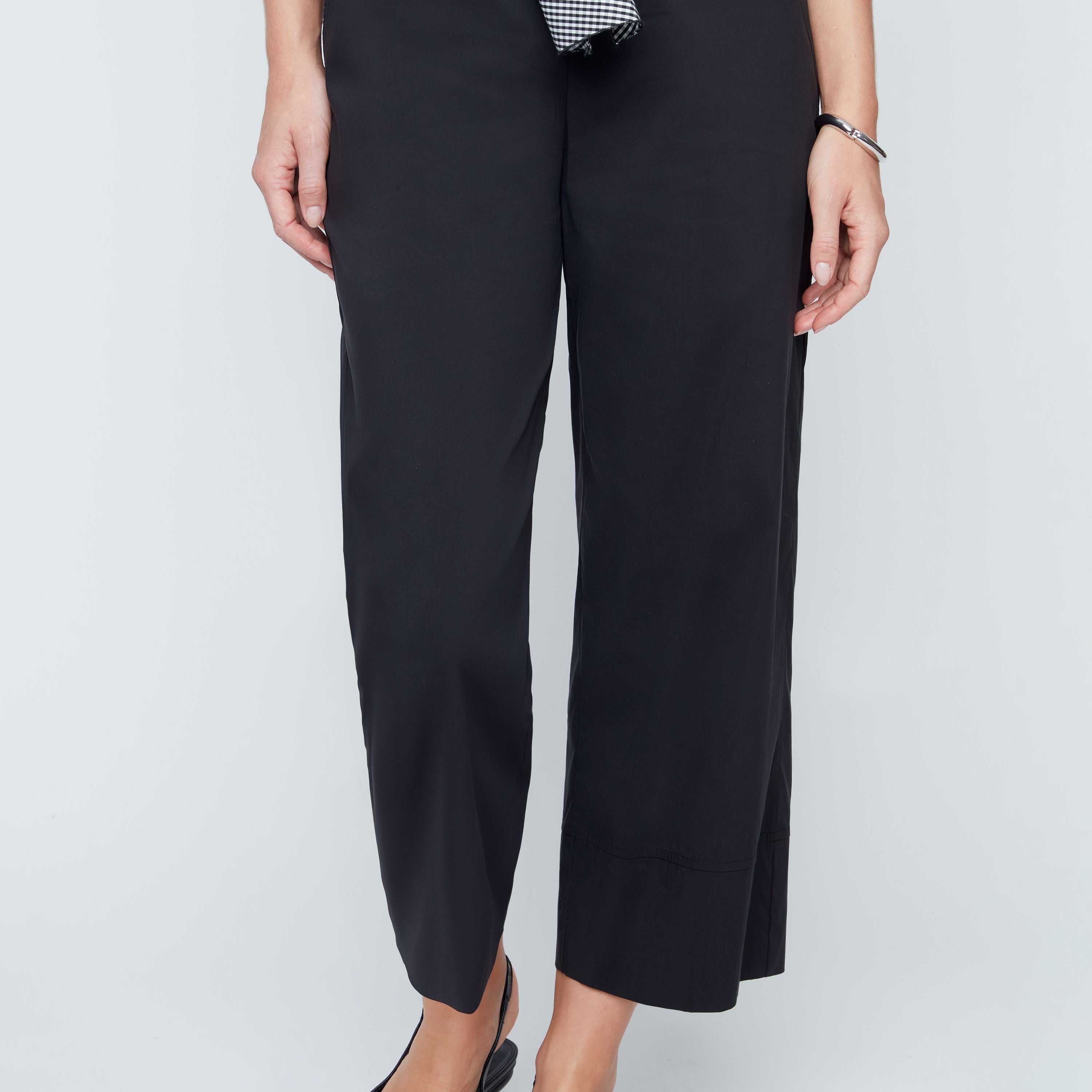 Person wearing black pants and a checkered top on a white background