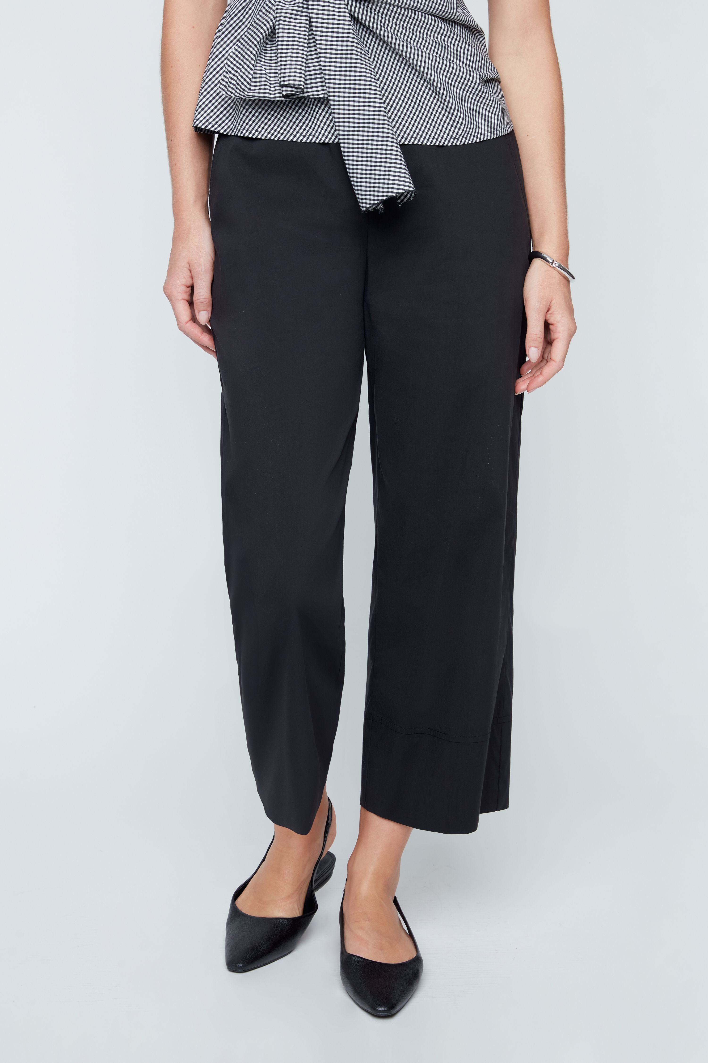 Person wearing black pants and a checkered top on a white background