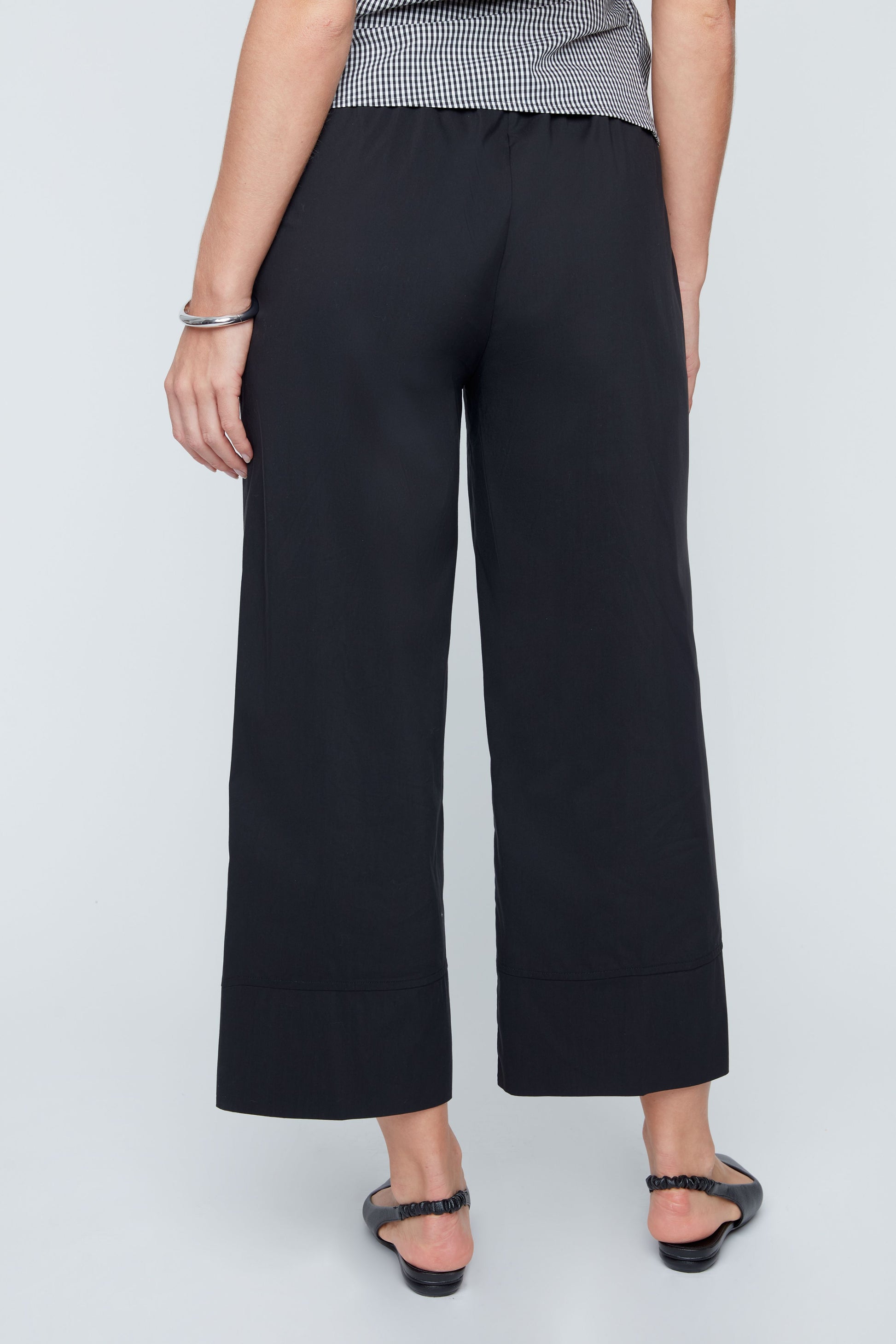 Person wearing black wide-leg pants on a white background